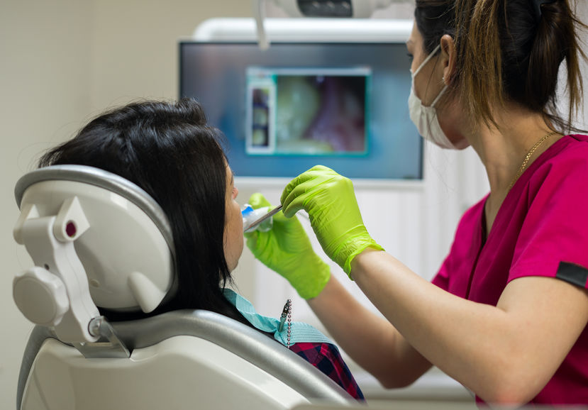 Dentist examining woman's teeth with camera