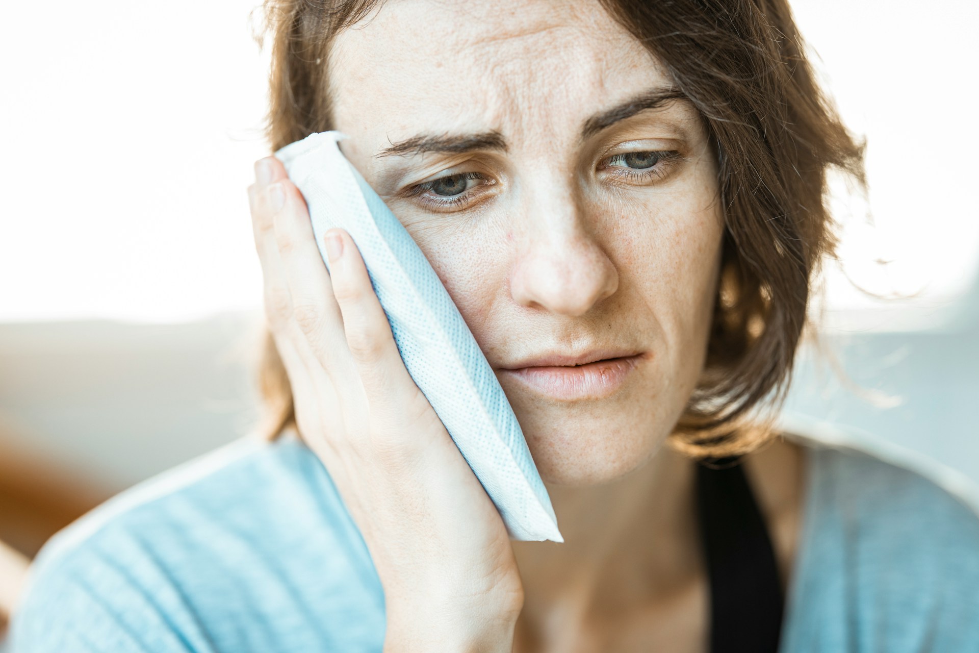 woman with icepack on jaw - what causes jaw pain